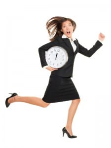 Stress - business woman running late with clock under her arm. Business concept photo with young businesswoman in a hurry running against time. Caucasian / Chinese Asian isolated on white background in full length.